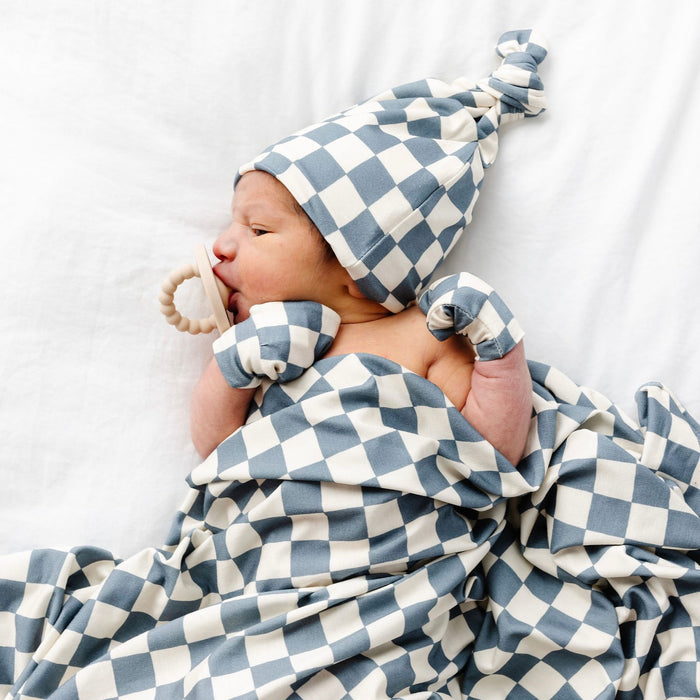 newborn baby wearing miles hat and mittens while wrapped in the miles swaddle blanket